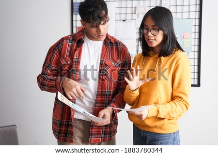 Male and female executives discussing over bulletin board in office while offering new ideas at the modern office. Stock photo