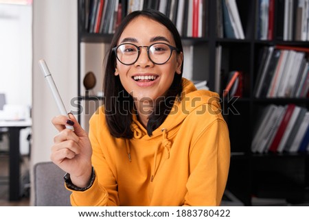 Young woman wearing glasses sitting at the desk with instruments, while working at the new project of the smartphone interface design. Stock photo