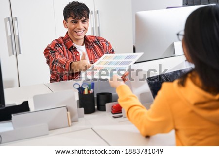 Give it to me. Portrait view of the female designer giving palette of colors to her male colleague while working at the modern light office