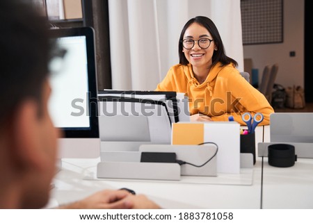 Designer sitting and working. Character, camera, computer, table and devices. Nice woman wearing glasses looking at the camera