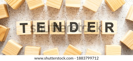 The word TENDER consists of wooden cubes with letters, top view on a light background. Work space.