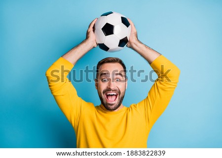 Photo of young crazy happy positive excited cheerful man hold football ball above head isolated on blue color background