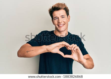 Handsome caucasian man wearing casual clothes smiling in love doing heart symbol shape with hands. romantic concept. 
