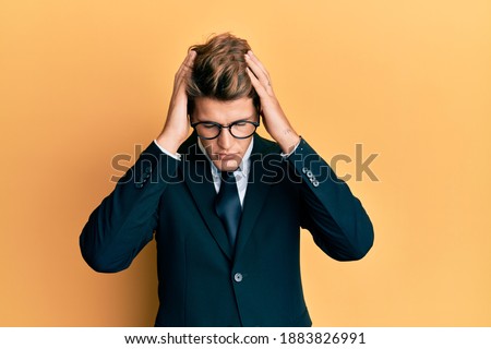 Handsome caucasian man wearing business suit and tie suffering from headache desperate and stressed because pain and migraine. hands on head. 
