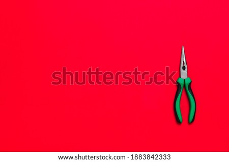 Quality green building pliers tool to compress something or repair a car or house on red background. Do it yourself instrument. Banner for advertising construction shop with copy space. Business card.