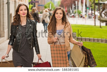 Couple of gorgeous young brunette women with shopping bags outdoors.