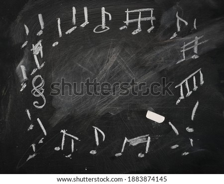 Notes, music symbols, signs frame and border drawn on black chalkboard with white chalk, blackboard background texture