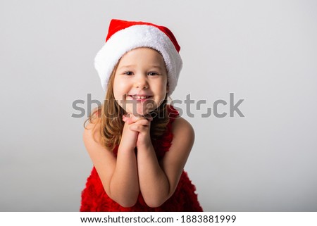 cute little girl in santa hat and red dress smiling on white background. The concept of new year and Christmas. New Year's Sale concept