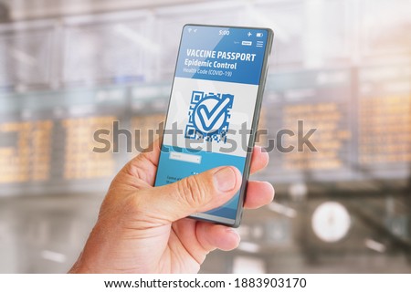 Smart phone with vaccine passport on screen for traveling with blurred background of flight schedule posters Royalty-Free Stock Photo #1883903170