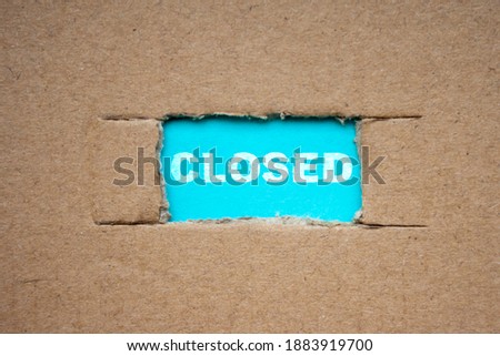 A cut-out hole in the paper cardboard, and under it a piece of paper with the word CLOSED. Coronavirus lockdown concept