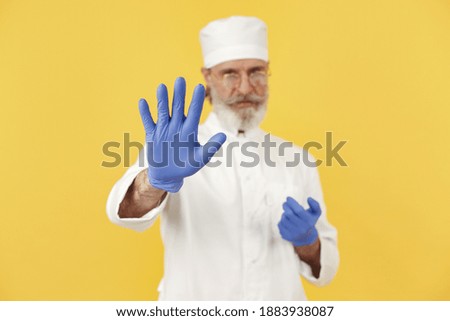 Smiling medical doctor in glasses. Isolated over yellow background. Man in a blue gloves.