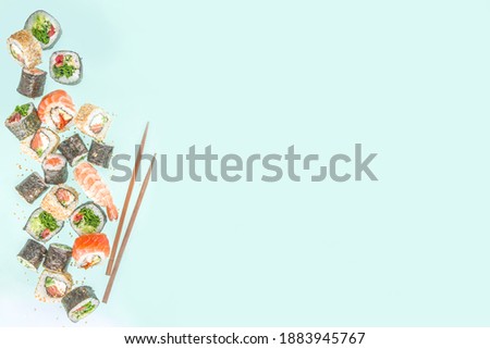 Flying sushi set with chopsticks. Various delicious japanese sushi, roll pieces and nigiri on light blue background