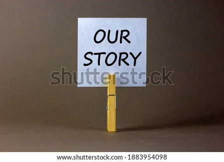 Our story symbol. White paper with words 'Our story', clip on wood clothespin. Beautiful grey background. Business and our story concept. Copy space.