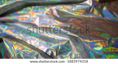 Iridescent fabric holographic background. Crumpled surface shiny metallic foil