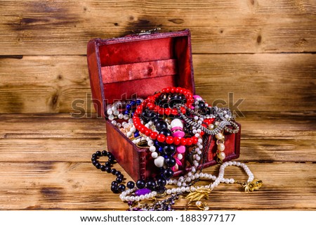Old box of red wood full of jewelry. Treasure chest
