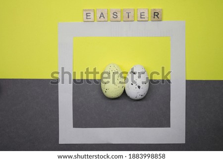 Easter decoration, designer eggs on gray and yellow background, white frame, flat image composition, top view.
