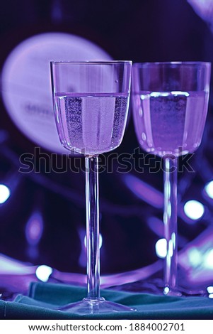selective focus photo of two glasses of champagne on the background of a vinyl record, surrounded by bright club illumination