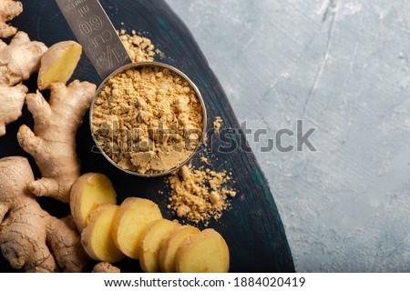 Ginger root and ginger powder in the bowl. Fresh ginger root and ground ginger spice. Royalty-Free Stock Photo #1884020419