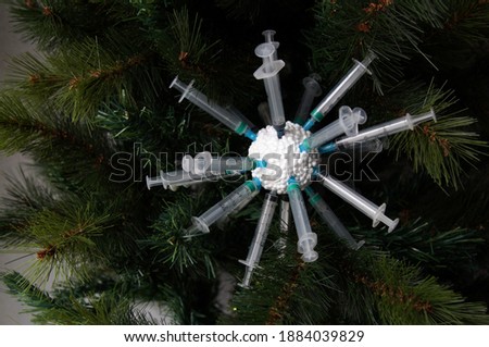 Christmas decoration on the fir tree - injection syringes stuck in a foam Christmas ball, symbolizing the coronavirus and the vaccine