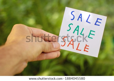 White paper with the words sale, sale, sale in three colors in a man's hand