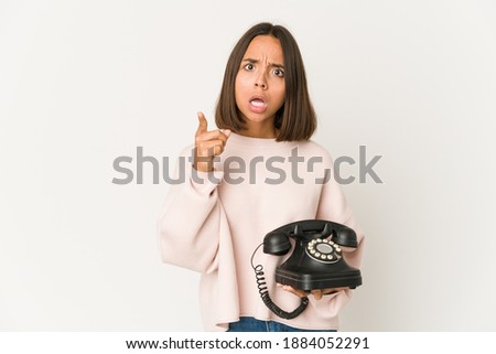 Young hispanic woman holding a vintage telephone isolated having an idea, inspiration concept.