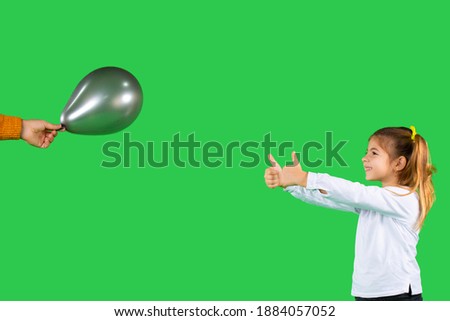 Photo with blank advertising space. The girl shows both fingers with thumb up on the ultimate gray balloon and smiles. High quality photo