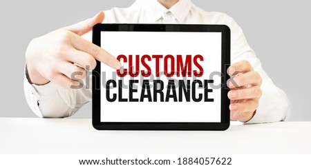 Text CUSTOMS CLEARANCE on tablet display in businessman hands on the white bakcground. Business concept