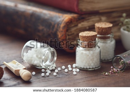 Bottles of homeopathic globules and old books. Homeopathy medicine concept. Royalty-Free Stock Photo #1884080587