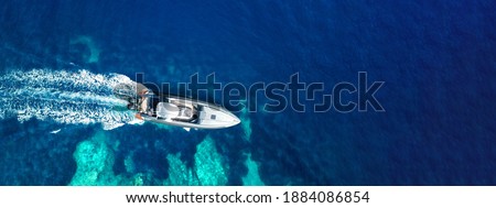Aerial drone ultra wide photo of inflatable rib power boat cruising in high speed in tropical exotic bay with coral reef and deep blue sea