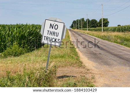 No thru trucks road sign along rural asphalt road. Concept of transportation, trucking, farming, and road damage 

