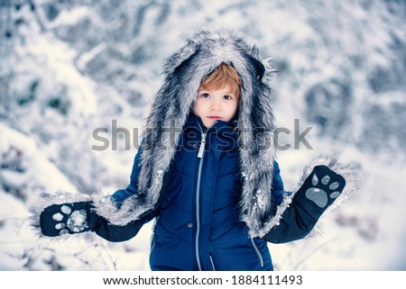 Winter landscape of forest and snow with cute child boy. Children run on snowy field. Boy dreams of winter time. Happy children on nature walks in the winter