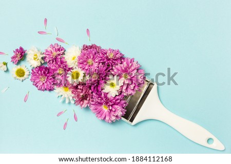 Flowers composition. Creative layout made of pink and white flowers and paint brush on pastel blue background. Flat lay, top view, copy space.