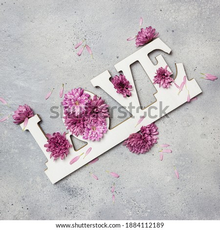 Floral Greeting card. Creative layout made of colorful flowers and word LOVE on gray stone background. Love concept. Flat lay.