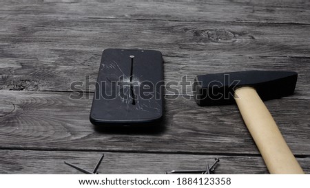 mobile phone pierced with a nail on a wooden background