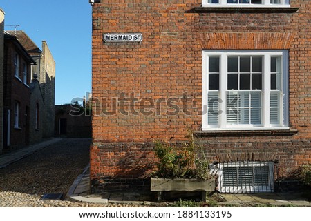 A street sign that says Mermaid Street, affixed to a classic brick house in Rye, England.  Image has copy space.
