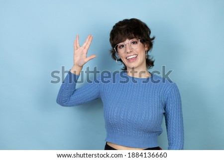 Young caucasian woman over isolated blue background doing hand symbol