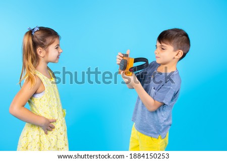 Boy photographer on a blue background take a photo ffor a little girl with a wooden decorative camera. High quality photo