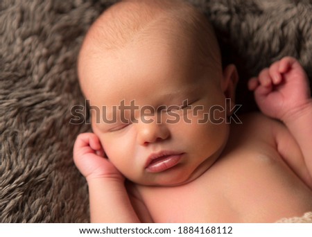 Caucasian new born baby, laying down peacefully asleep, headshot, studio light used.