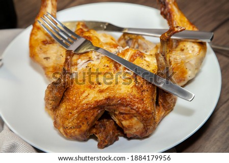 Fork and knife on a cut, roasted chicken