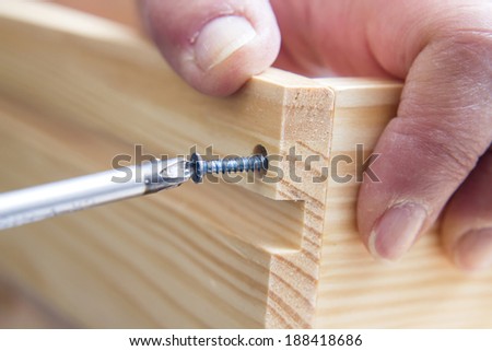 A carpenter builds a small white table with a screwdriver Royalty-Free Stock Photo #188418686