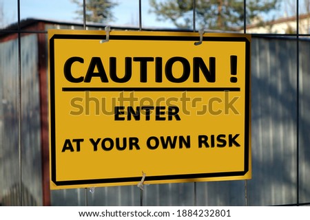 Board informing on the fence, caution enter at your own risk