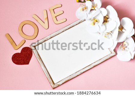 Valentines day concept. Valentine's Day background. Orchid and wooden frame on a pink background. Flat lay, top view, copy space. Valentine's Day card.
