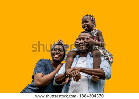 Happy African families with a daughter riding their father's neck with yellow backgrounds, color trend 2021.