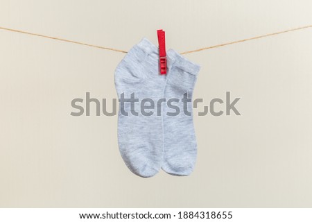 multicolored socks, dry after washing, hanging on a clothesline with clothespins on a light background
