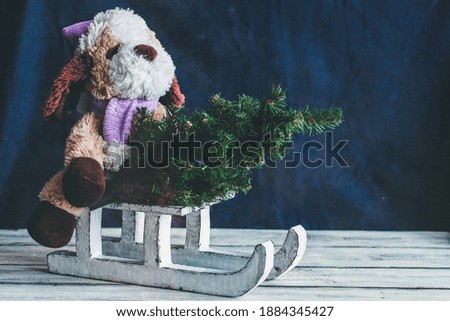 Decorative winter sleigh. White sleigh. A soft toy and a Christmas tree on a sleigh. Christmas decor. Good New Year spirit