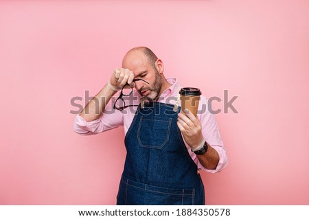 Tired bald mature man with coffee in recyclable cardboard cup