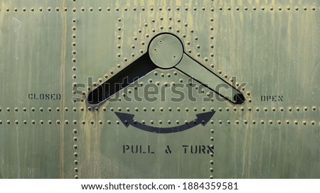 Closeup of the latch on the door of a military plane with rivets on weathered fuselage Royalty-Free Stock Photo #1884359581