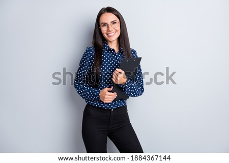Portrait of lovely cheerful businesslady secretary holding in hands clipboard isolated on grey pastel color background Royalty-Free Stock Photo #1884367144