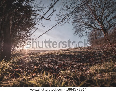 A frozen misty field at sunrise. The layers mist settle over the lower ground across a classic British countryside view at sunrise in winter.