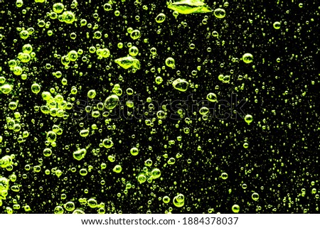 Close-up of air bubbles under water against black background.